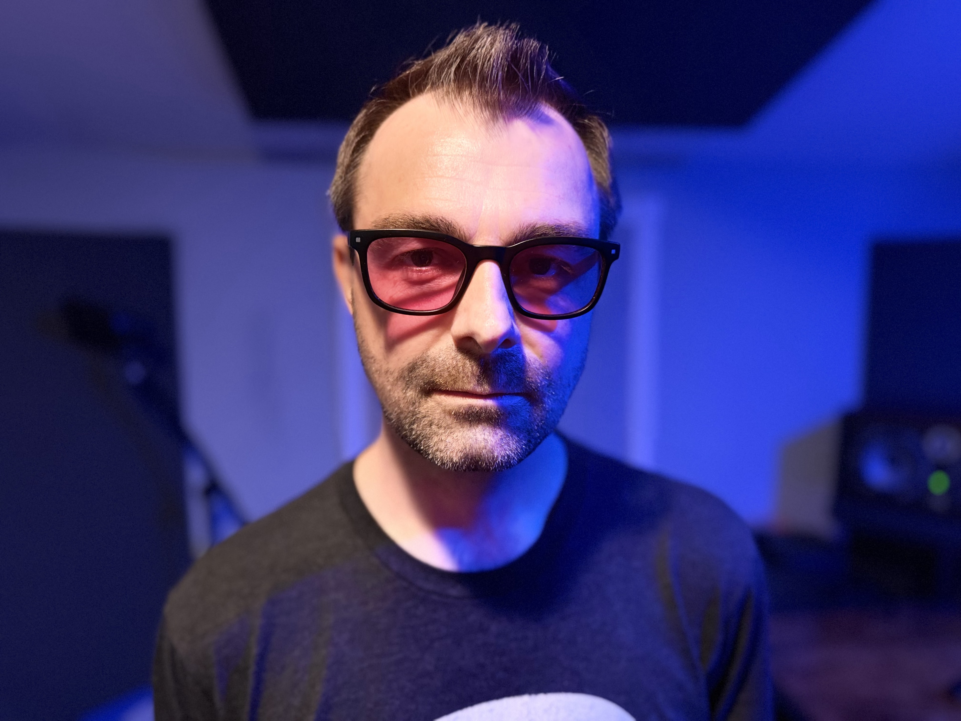 Episode In Apathy artist in glasses under blue and purple recording studio lights