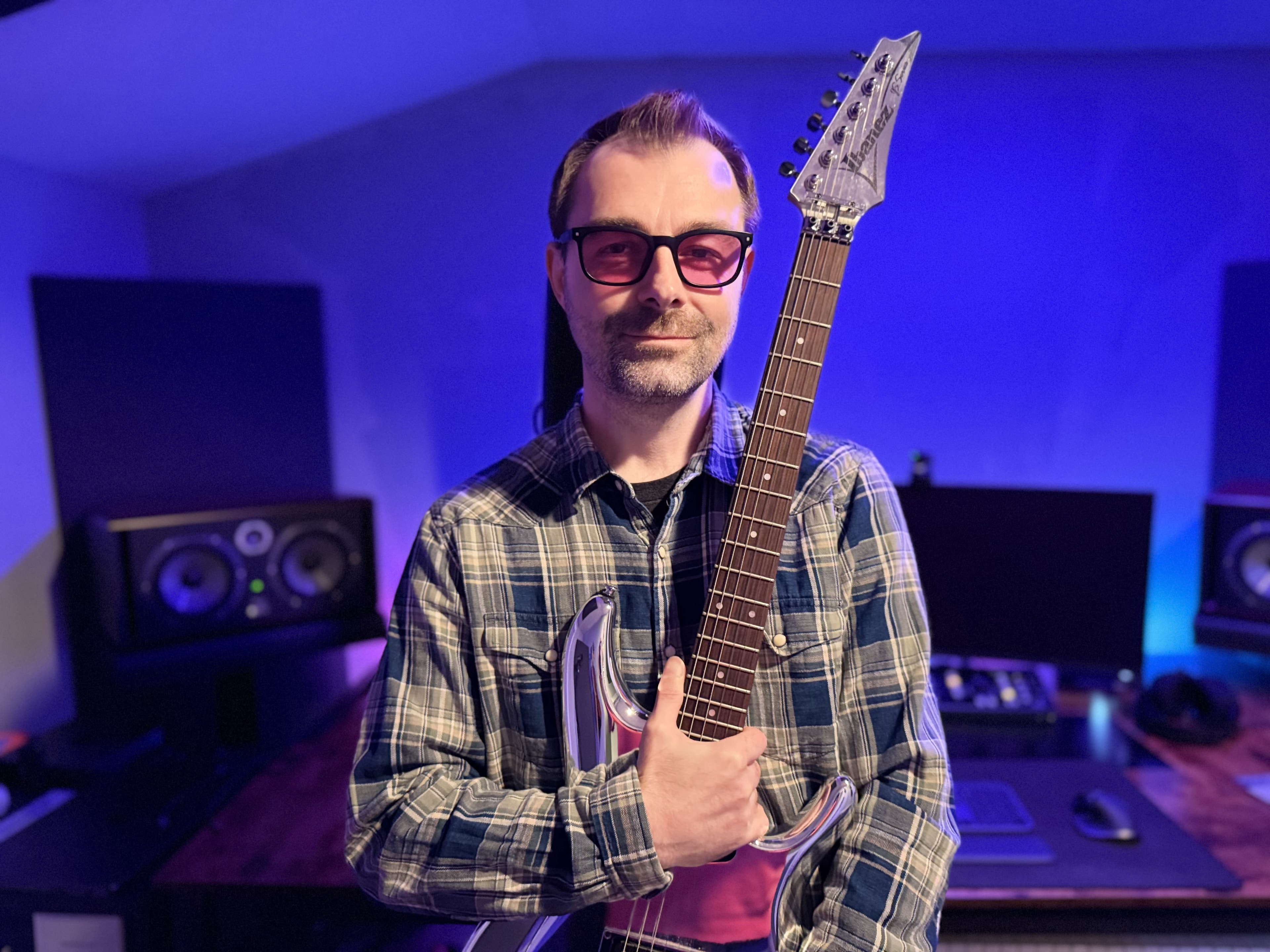 Episode In Apathy artist holding an electric guitar in a blue-lit recording studio