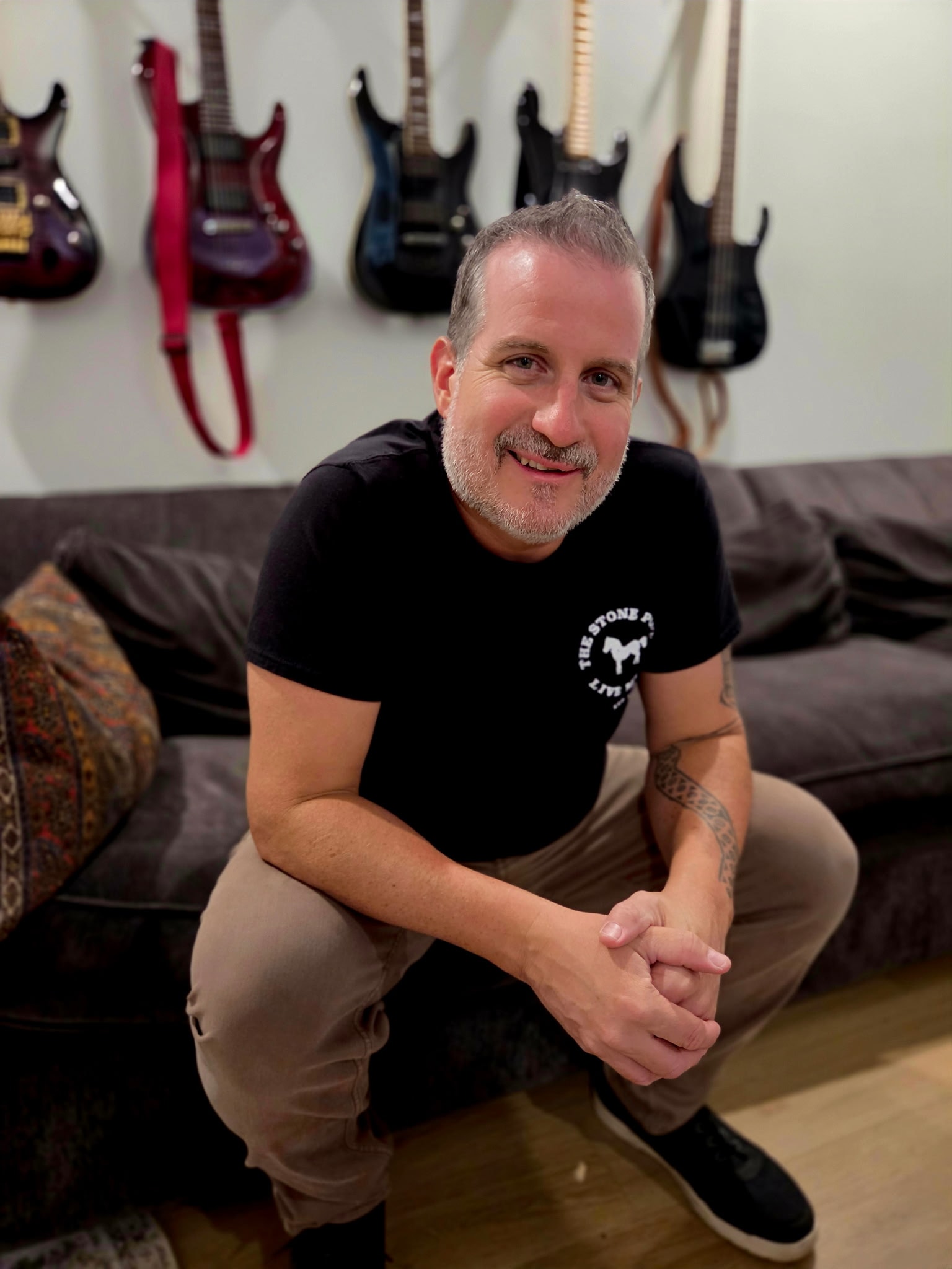 Episode In Apathy artist seated in a music room with guitars behind him